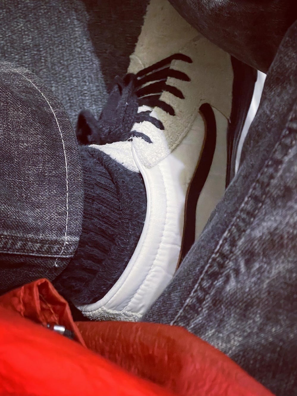 オレンジ系のナイロンジャケット、ブラック系のデニムパンツ、ホワイト系のスニーカーを着用したメンズの春コーディネートの3枚目の写真