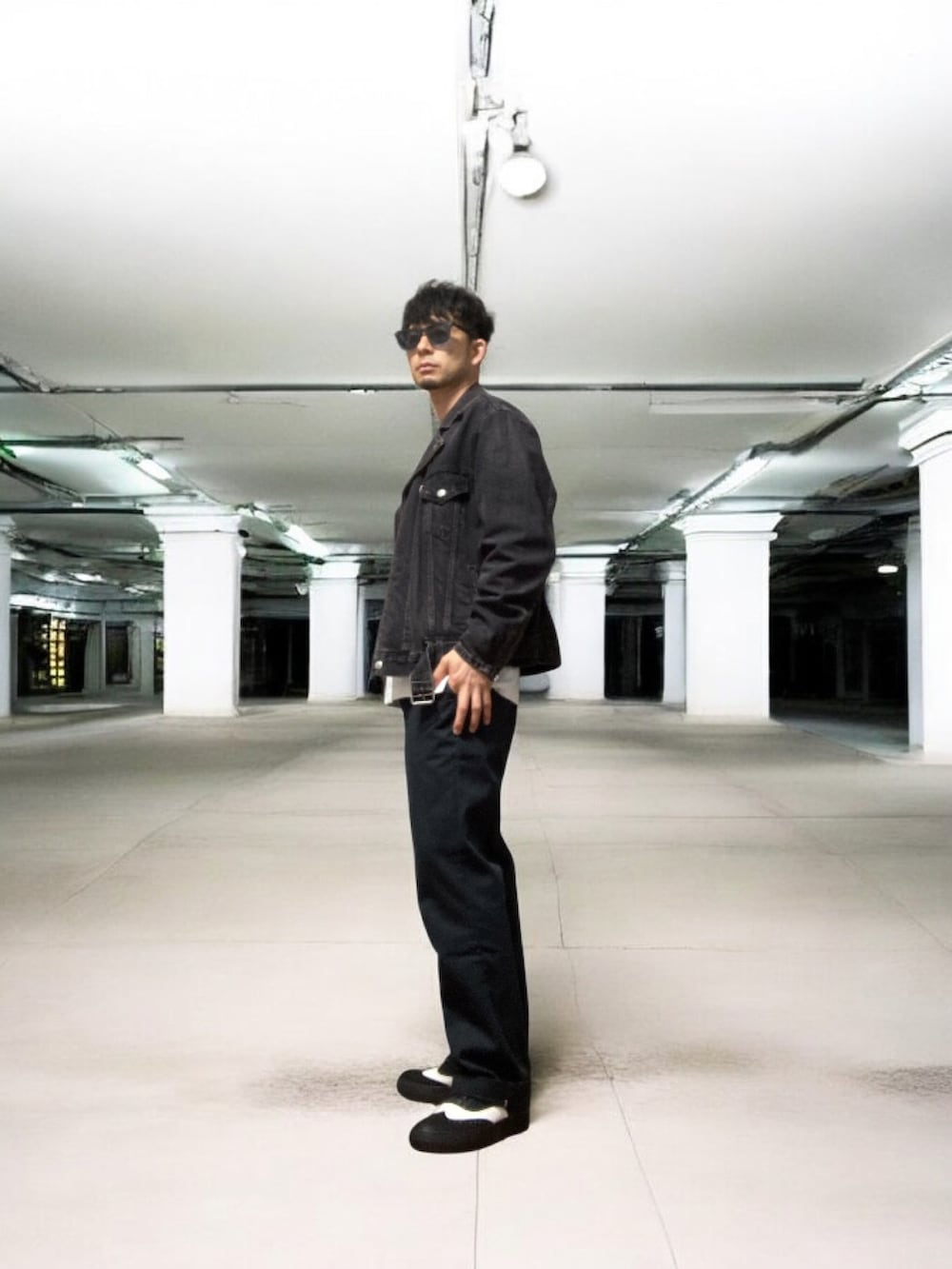 ブラック系のライダースジャケット、ブルー系のチノパンツ、ブラック系のスニーカーを着用したメンズの春コーディネートの3枚目の写真