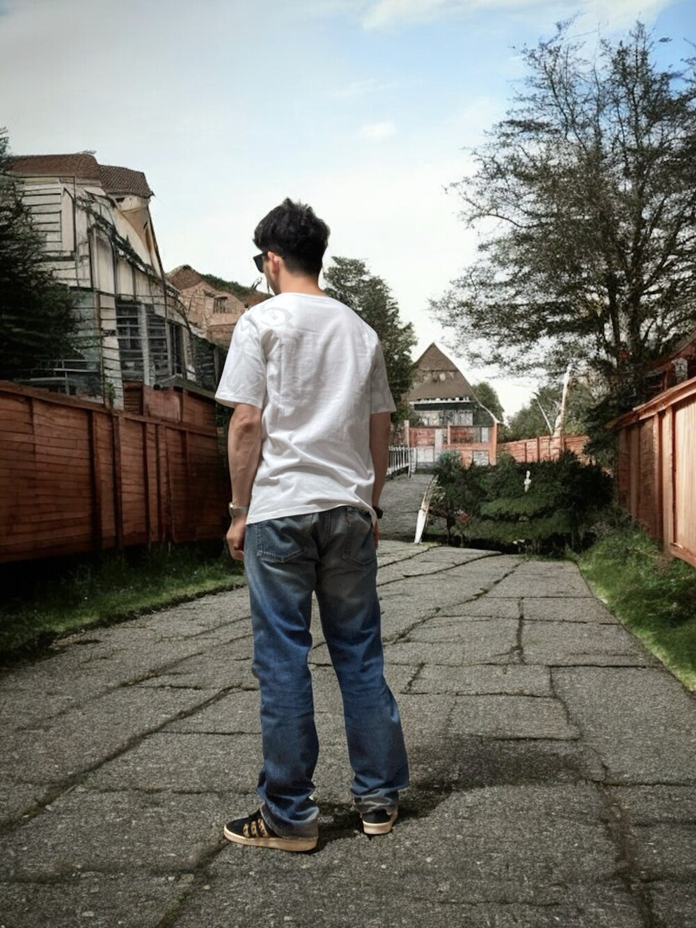 ブラック系のスニーカー、ホワイト系のTシャツ/カットソー、ブルー系のデニムパンツを着用したメンズの夏コーディネートの4枚目の写真