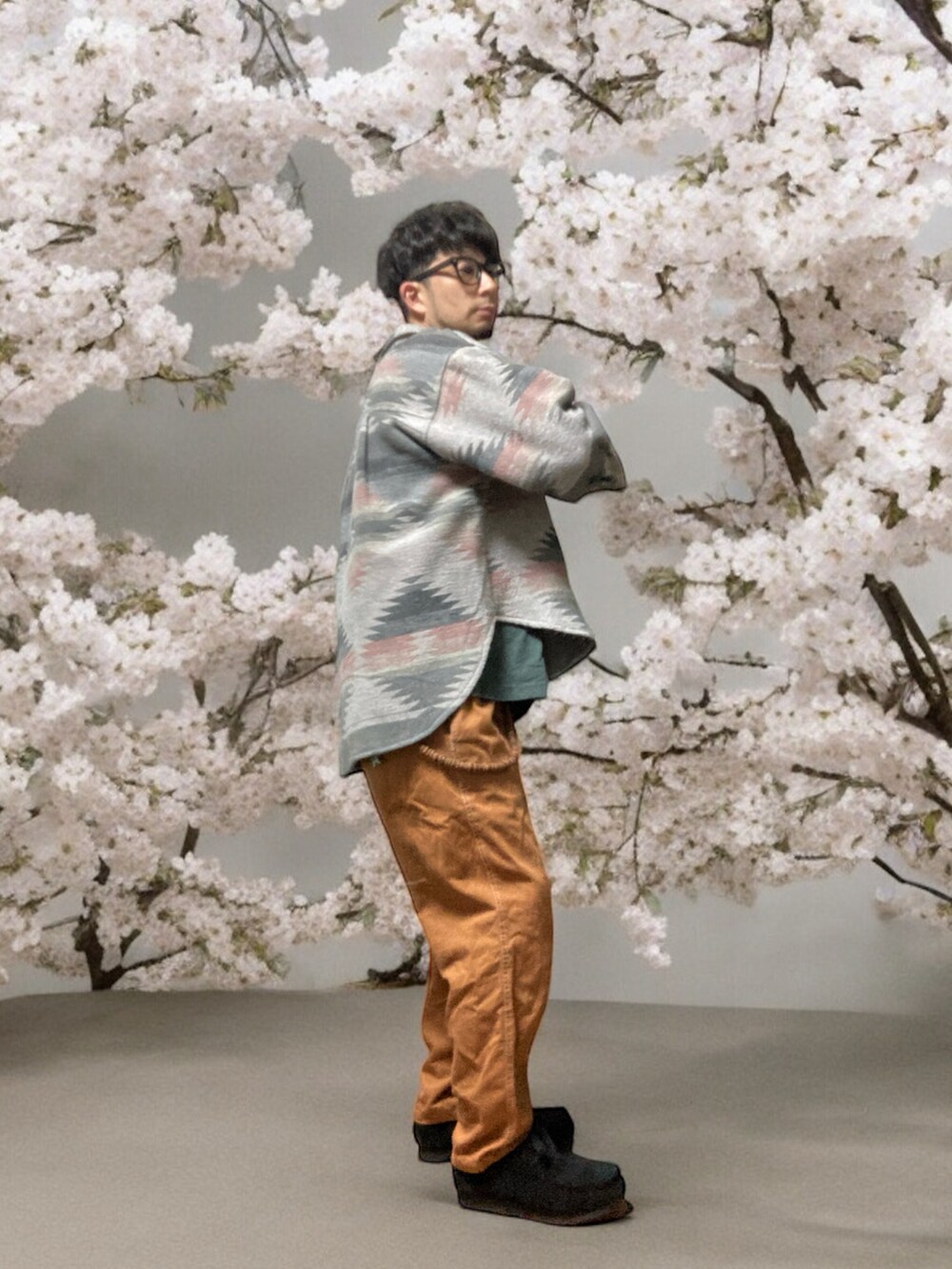 ブラウン系のチノパンツ、ブラック系のモカシン/デッキシューズ、グリーン系のTシャツ/カットソーを着用したメンズの春コーディネートの3枚目の写真