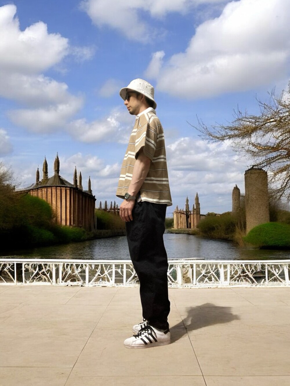 ブラック系のデニムパンツ、ブラウン系のポロシャツ、ホワイト系のスニーカーを着用したメンズの夏コーディネートの3枚目の写真