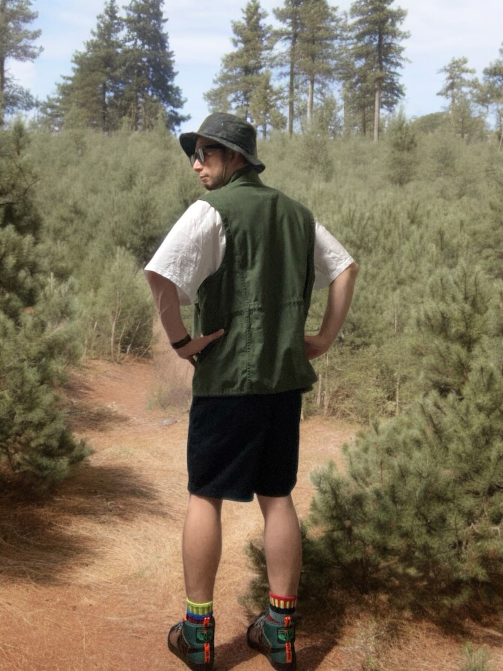 ブラック系のチノパンツ、ブラウン系のスニーカー、グリーン系のベストを着用したメンズの春コーディネートの3枚目の写真