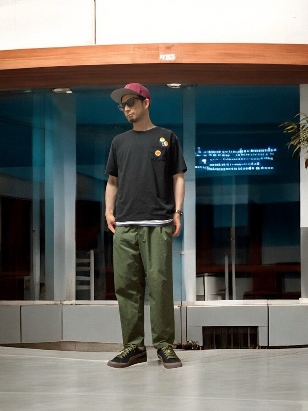 ブラック系のTシャツ/カットソー、グリーン系のスラックス、ブルー系のタンクトップを着用したメンズの夏コーディネートの2枚目の写真