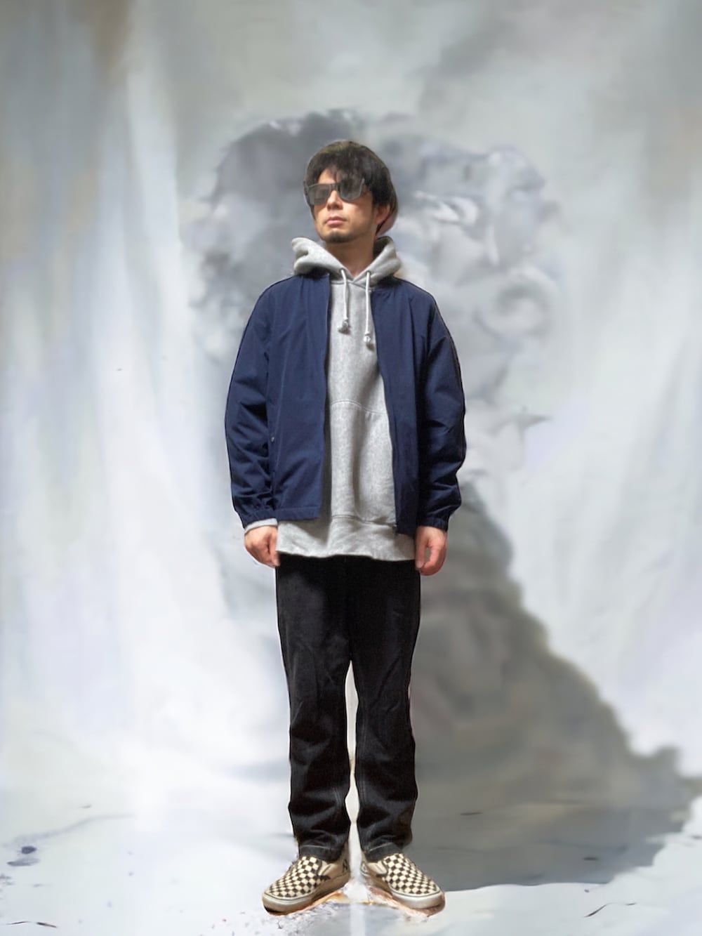 ブラック系のチノパンツ、ブルー系のノーカラージャケット、グレー系のパーカーを着用したメンズの春コーディネートの2枚目の写真