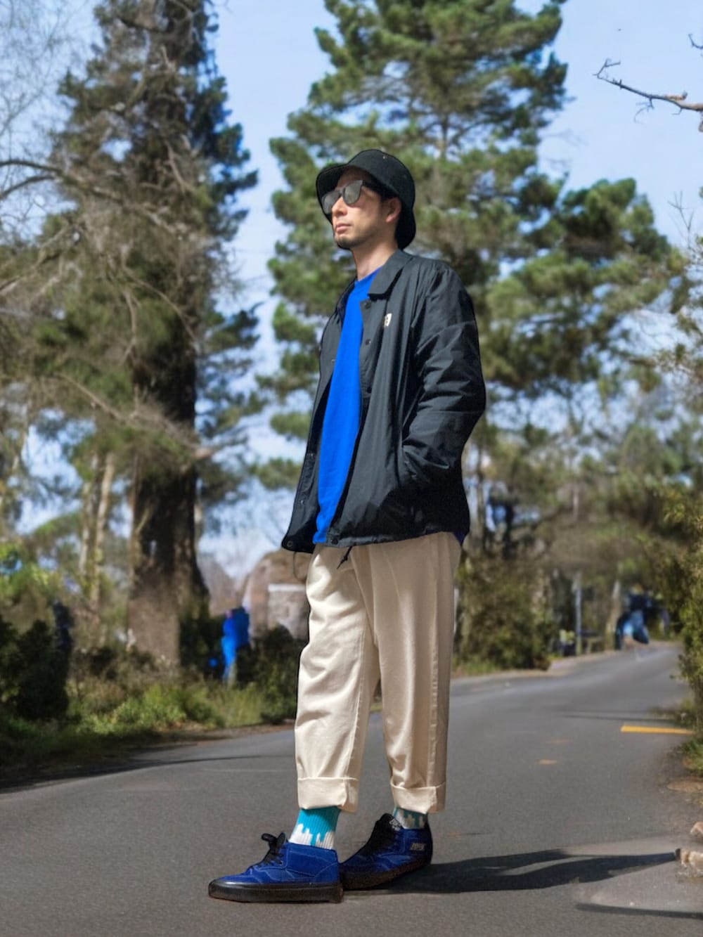 ホワイト系のチノパンツ、ブルー系のスニーカー、ブラック系のナイロンジャケットを着用したメンズの春コーディネートの2枚目の写真
