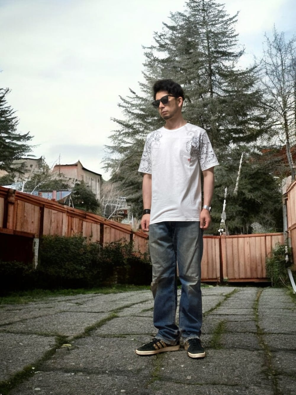 ブラック系のスニーカー、ホワイト系のTシャツ/カットソー、ブルー系のデニムパンツを着用したメンズの夏コーディネートの2枚目の写真