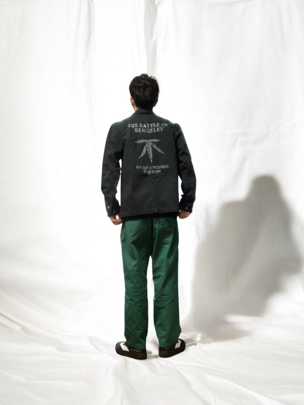 グリーン系のチノパンツ、ブラック系のスニーカー、ブラック系のジャケット/アウターを着用したメンズの春コーディネートの4枚目の写真