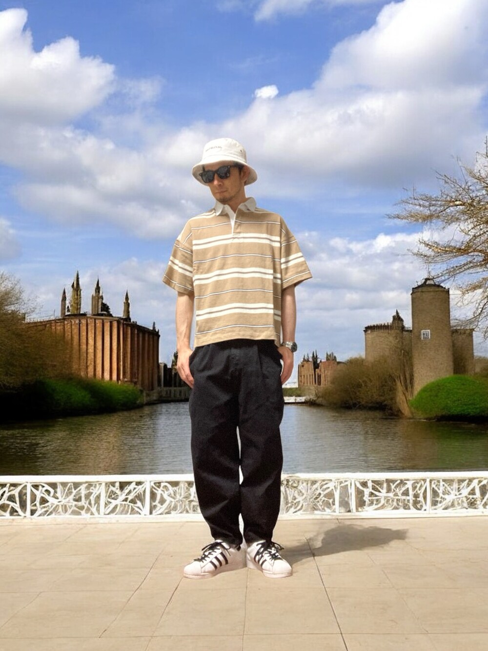 ブラック系のデニムパンツ、ブラウン系のポロシャツ、ホワイト系のスニーカーを着用したメンズの夏コーディネートの2枚目の写真