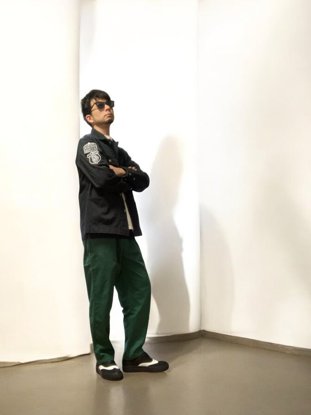 グリーン系のチノパンツ、ブラック系のスニーカー、ブラック系のジャケット/アウターを着用したメンズの春コーディネートの2枚目の写真