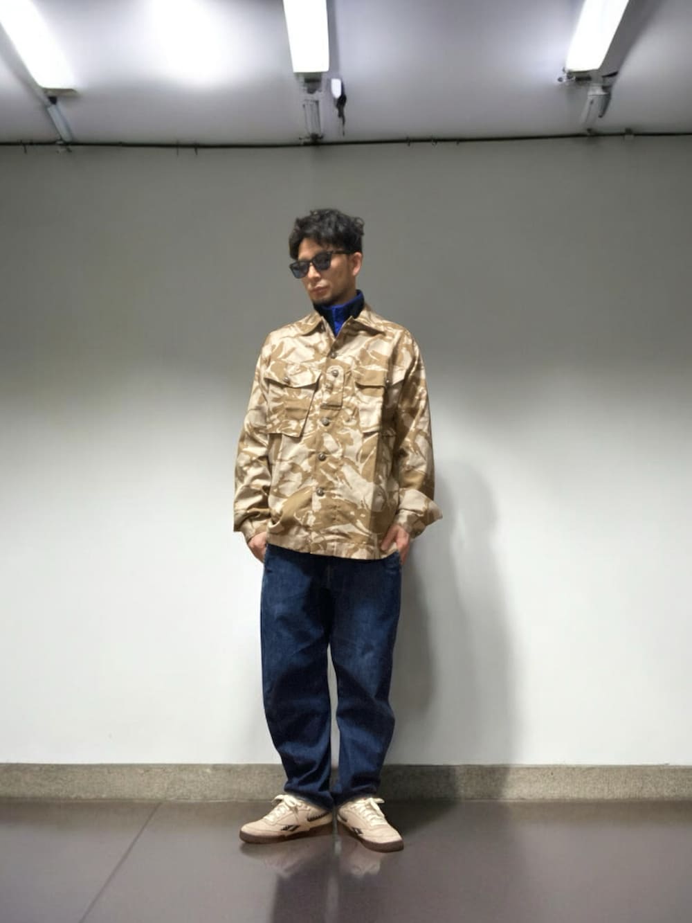 ベージュ系のスニーカー、その他のミリタリージャケット、ブルー系のデニムパンツを着用したメンズの冬コーディネートの3枚目の写真