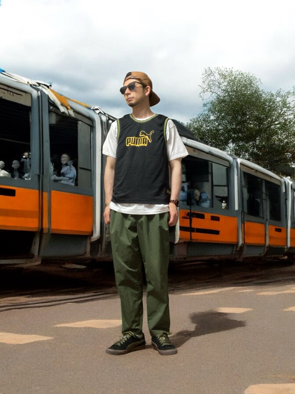 ブラック系のスニーカー、ブラック系のタンクトップ、グリーン系のスラックスを着用したメンズの夏コーディネートの2枚目の写真