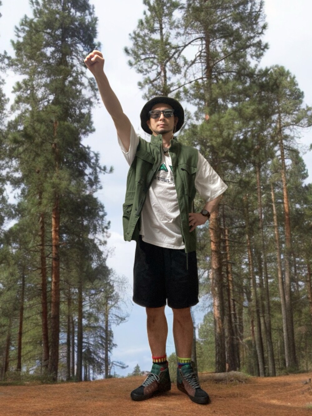 ブラック系のチノパンツ、ブラウン系のスニーカー、グリーン系のベストを着用したメンズの春コーディネートの4枚目の写真