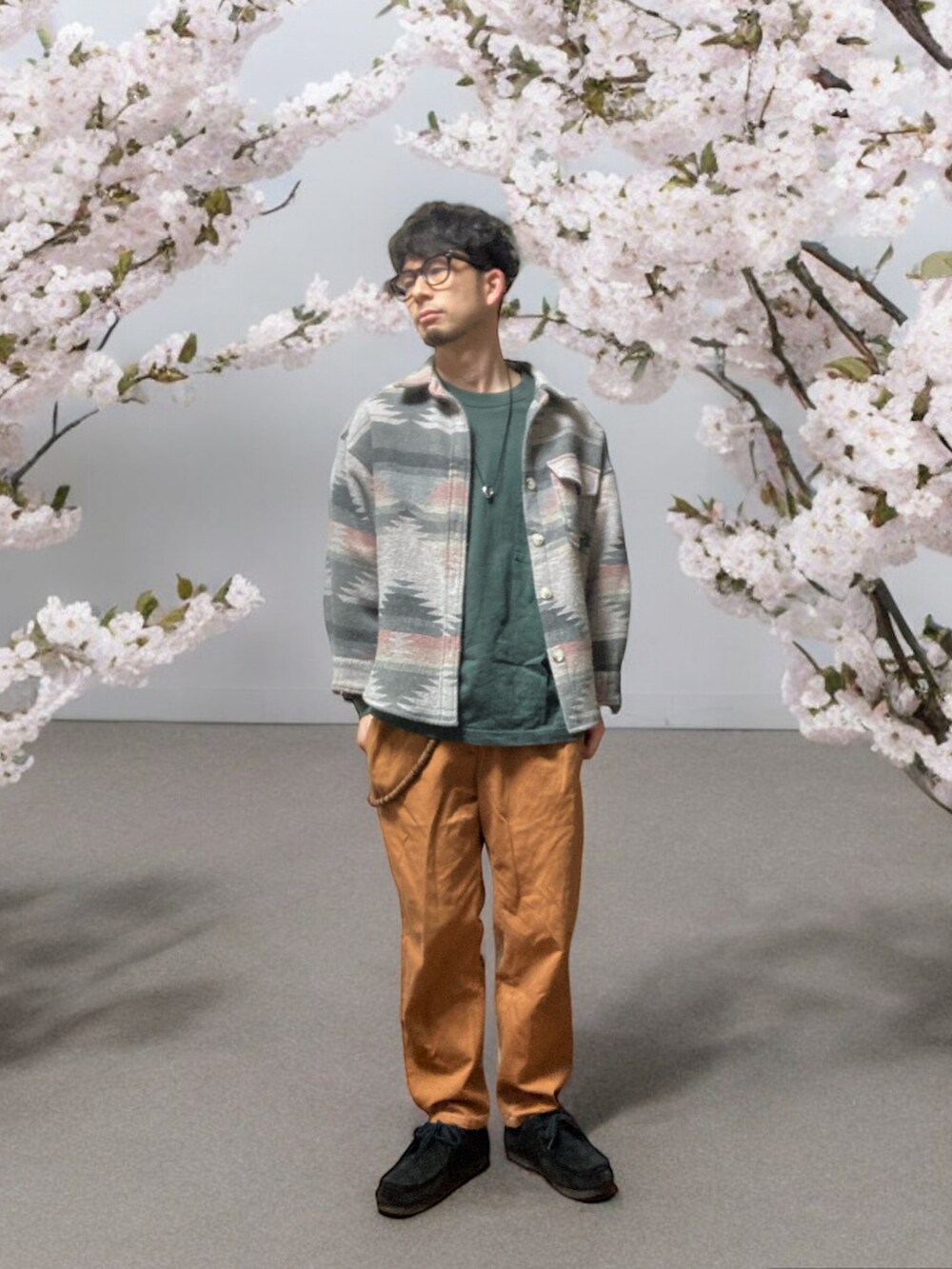 ブラウン系のチノパンツ、ブラック系のモカシン/デッキシューズ、グリーン系のTシャツ/カットソーを着用したメンズの春コーディネートの5枚目の写真