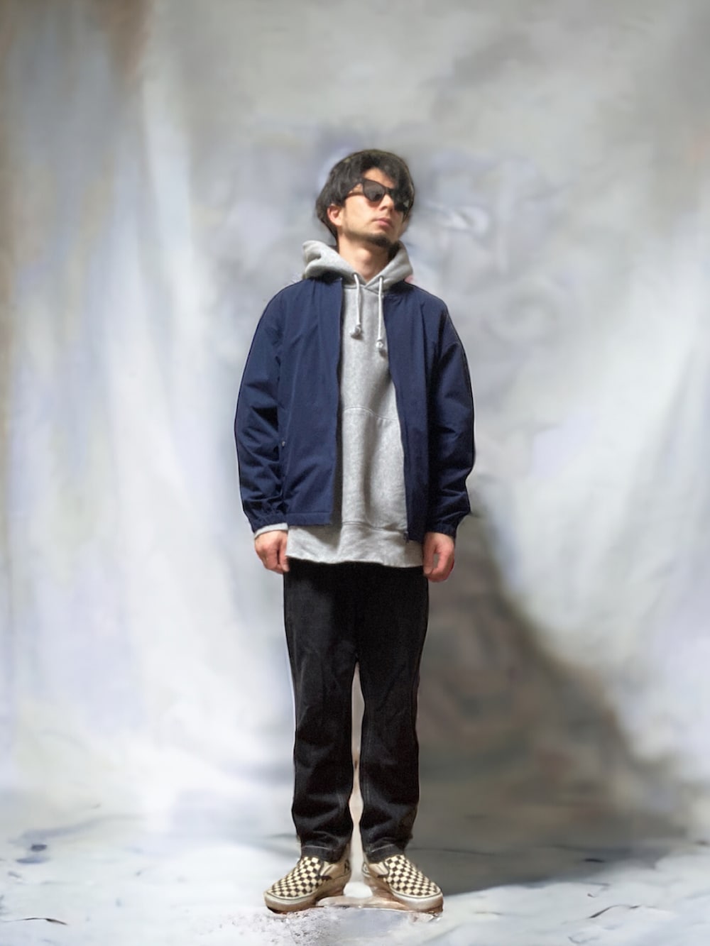 ブラック系のチノパンツ、ブルー系のノーカラージャケット、グレー系のパーカーを着用したメンズの春コーディネートの3枚目の写真