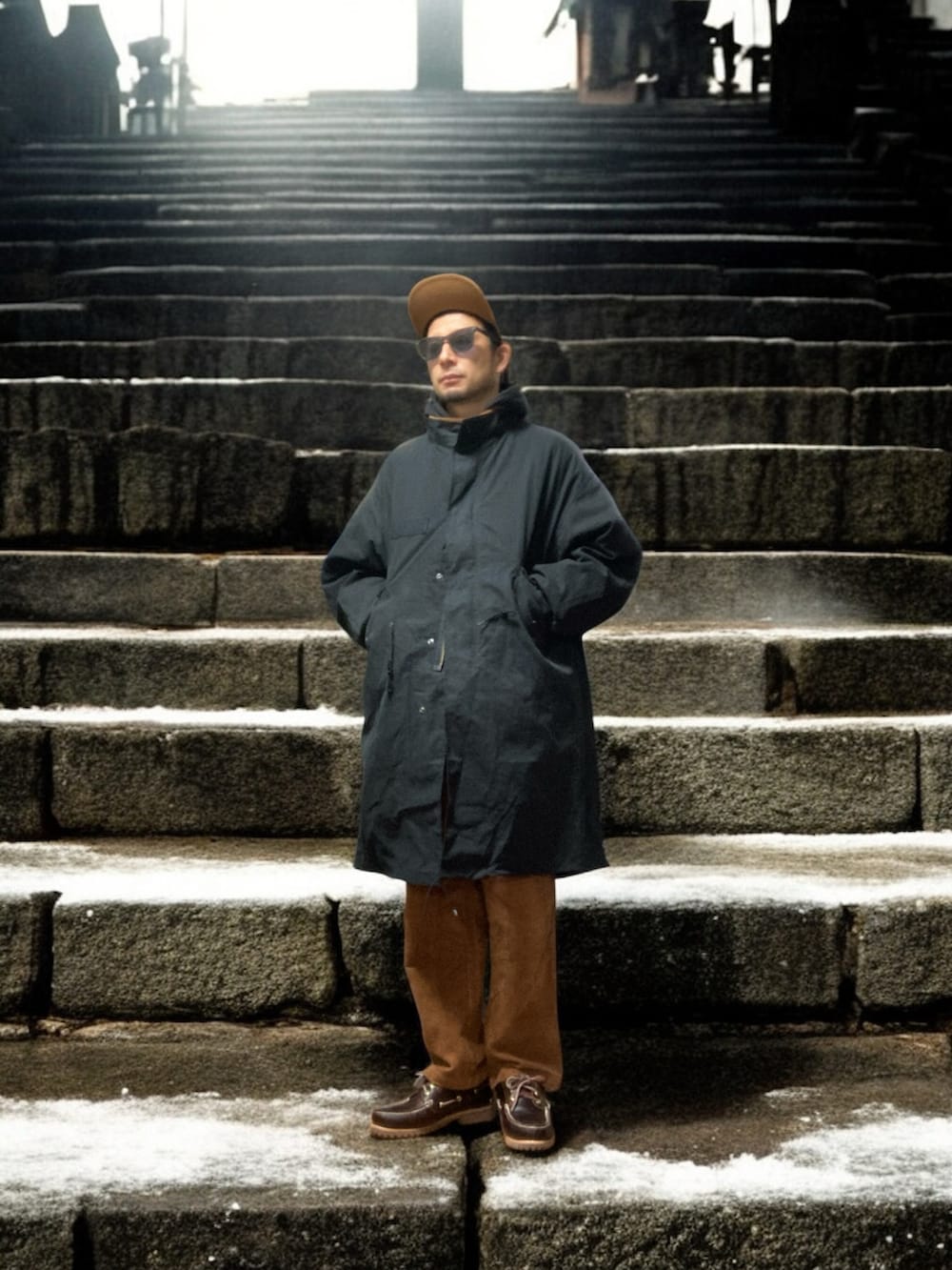 ブラック系のモッズコート、ブラウン系のその他パンツ、ブラウン系のモカシン/デッキシューズを着用したメンズの冬コーディネートの2枚目の写真