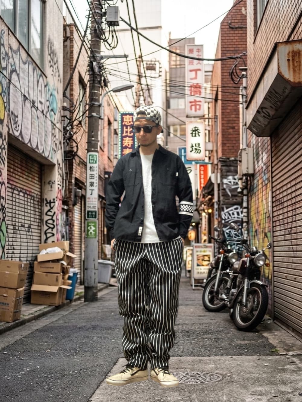 ブラック系のシャツ/ブラウス、ブラック系のチノパンツ、ホワイト系のスニーカーを着用したメンズの春コーディネートの2枚目の写真