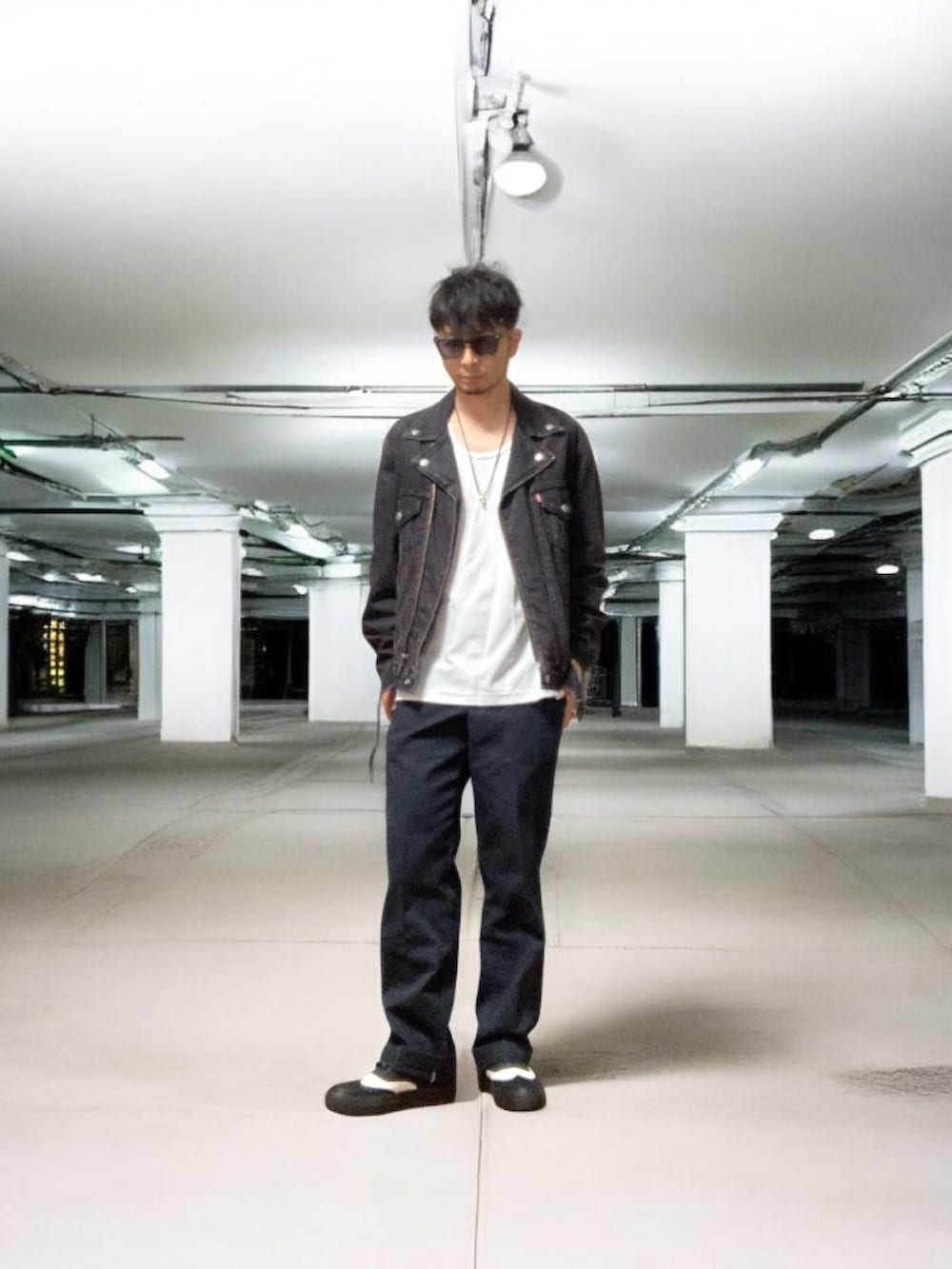 ブラック系のライダースジャケット、ブルー系のチノパンツ、ブラック系のスニーカーを着用したメンズの春コーディネートの2枚目の写真