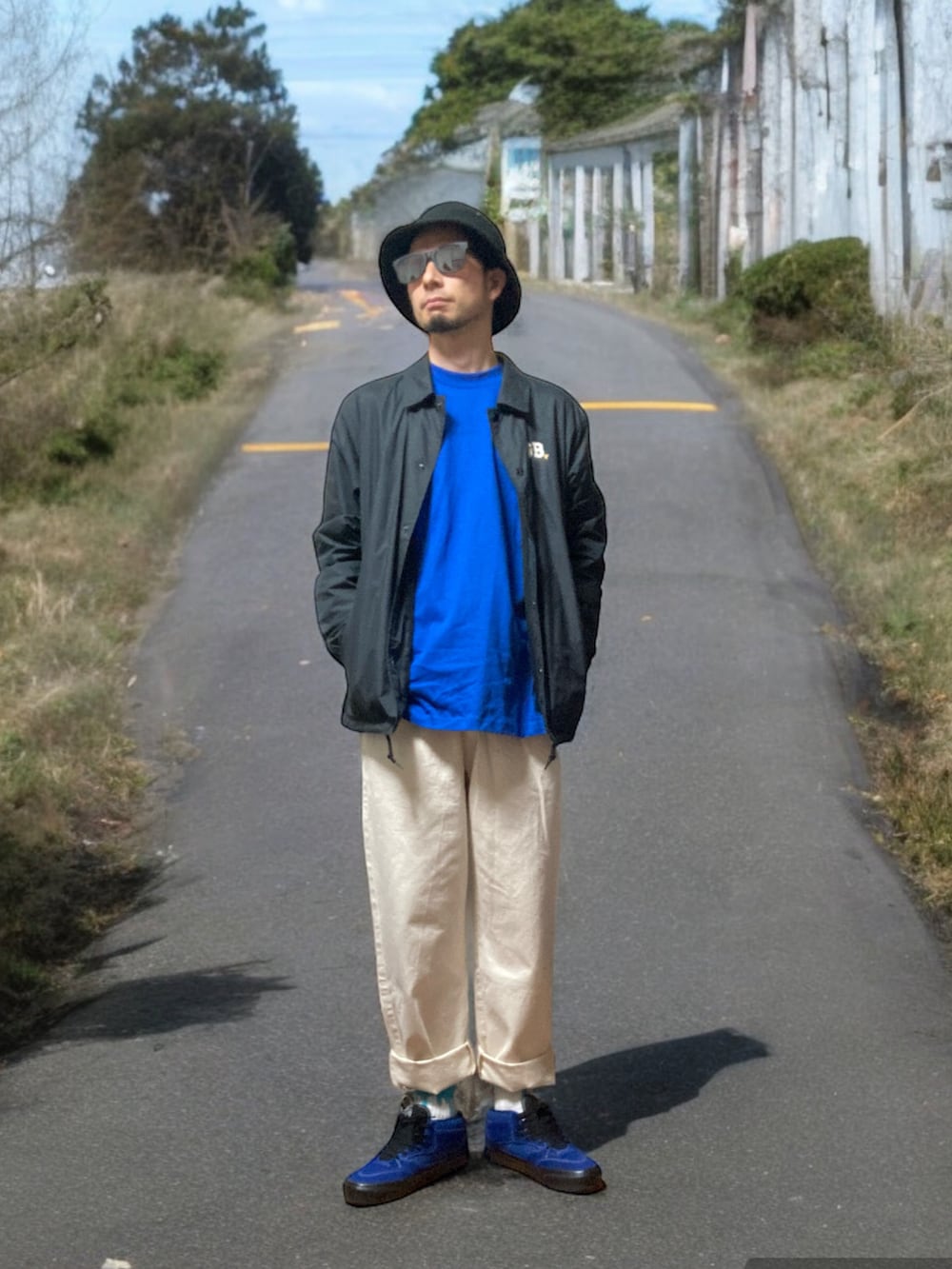 ホワイト系のチノパンツ、ブルー系のスニーカー、ブラック系のナイロンジャケットを着用したメンズの春コーディネートの4枚目の写真