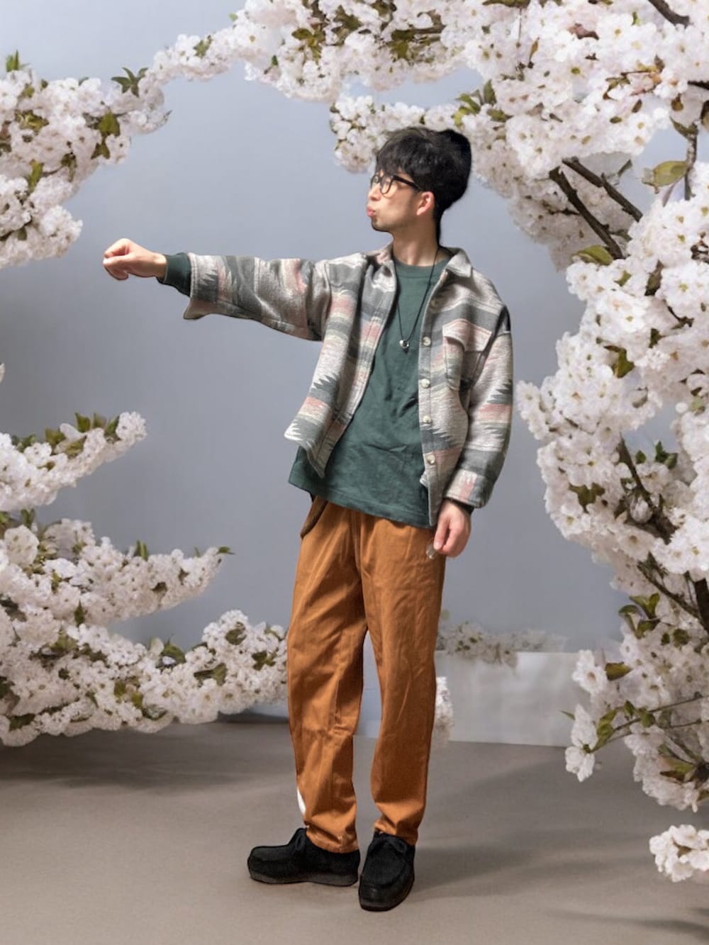 ブラウン系のチノパンツ、ブラック系のモカシン/デッキシューズ、グリーン系のTシャツ/カットソーを着用したメンズの春コーディネートの2枚目の写真