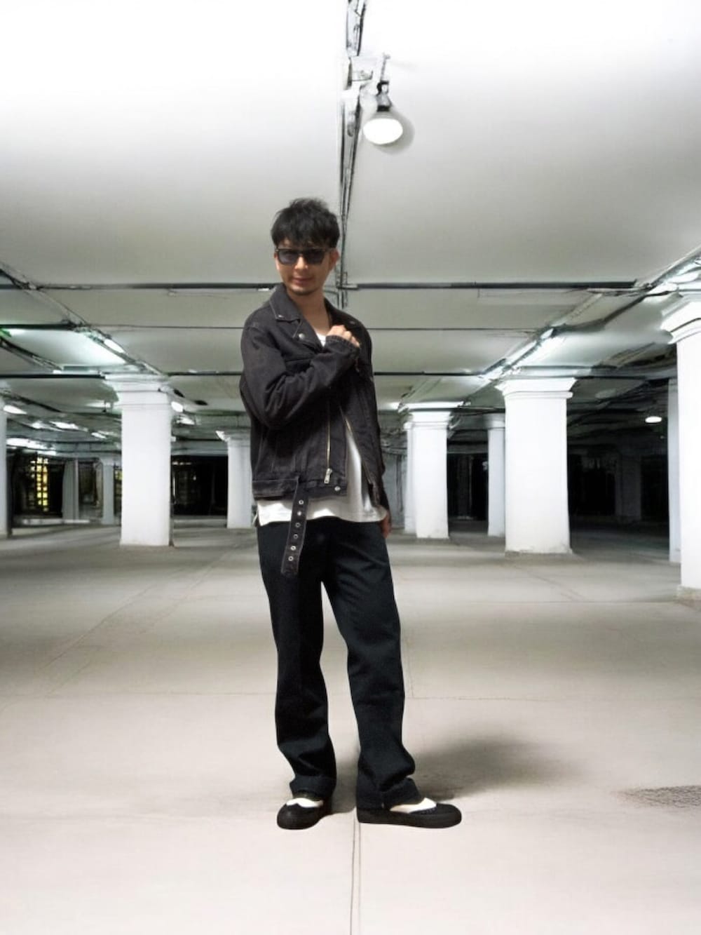 ブラック系のライダースジャケット、ブルー系のチノパンツ、ブラック系のスニーカーを着用したメンズの春コーディネートの4枚目の写真