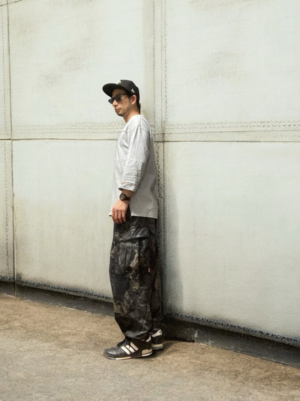 グレー系のTシャツ/カットソー、ブラック系のカーゴパンツ、ブラック系のスニーカーを着用したメンズの秋コーディネートの2枚目の写真