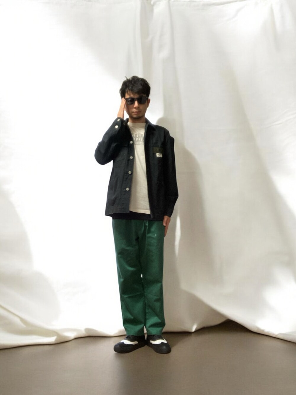 グリーン系のチノパンツ、ブラック系のスニーカー、ブラック系のジャケット/アウターを着用したメンズの春コーディネートの5枚目の写真