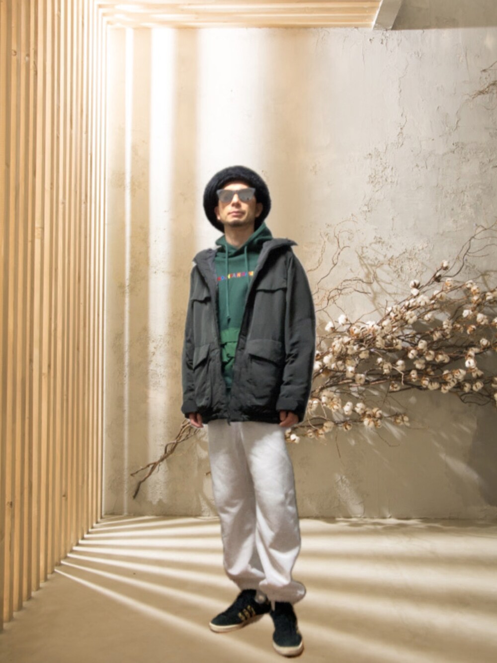ホワイト系のスウェットパンツ、ブラック系のスニーカー、グリーン系のパーカーを着用したメンズの冬コーディネートの2枚目の写真