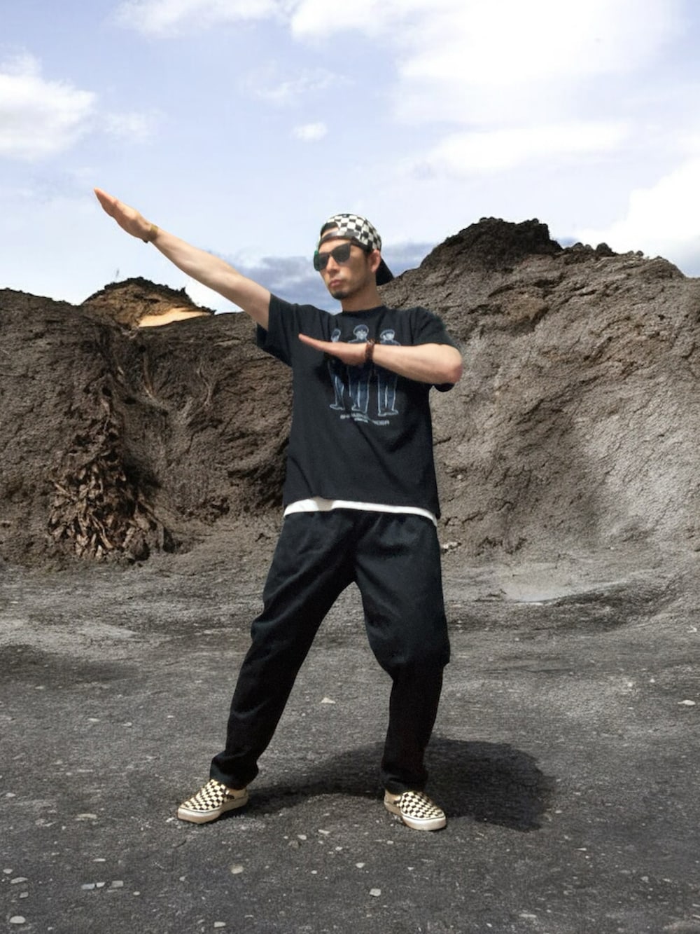 ブラック系のTシャツ/カットソー、ブラック系のチノパンツ、ホワイト系のスリッポンを着用したメンズの夏コーディネートの5枚目の写真