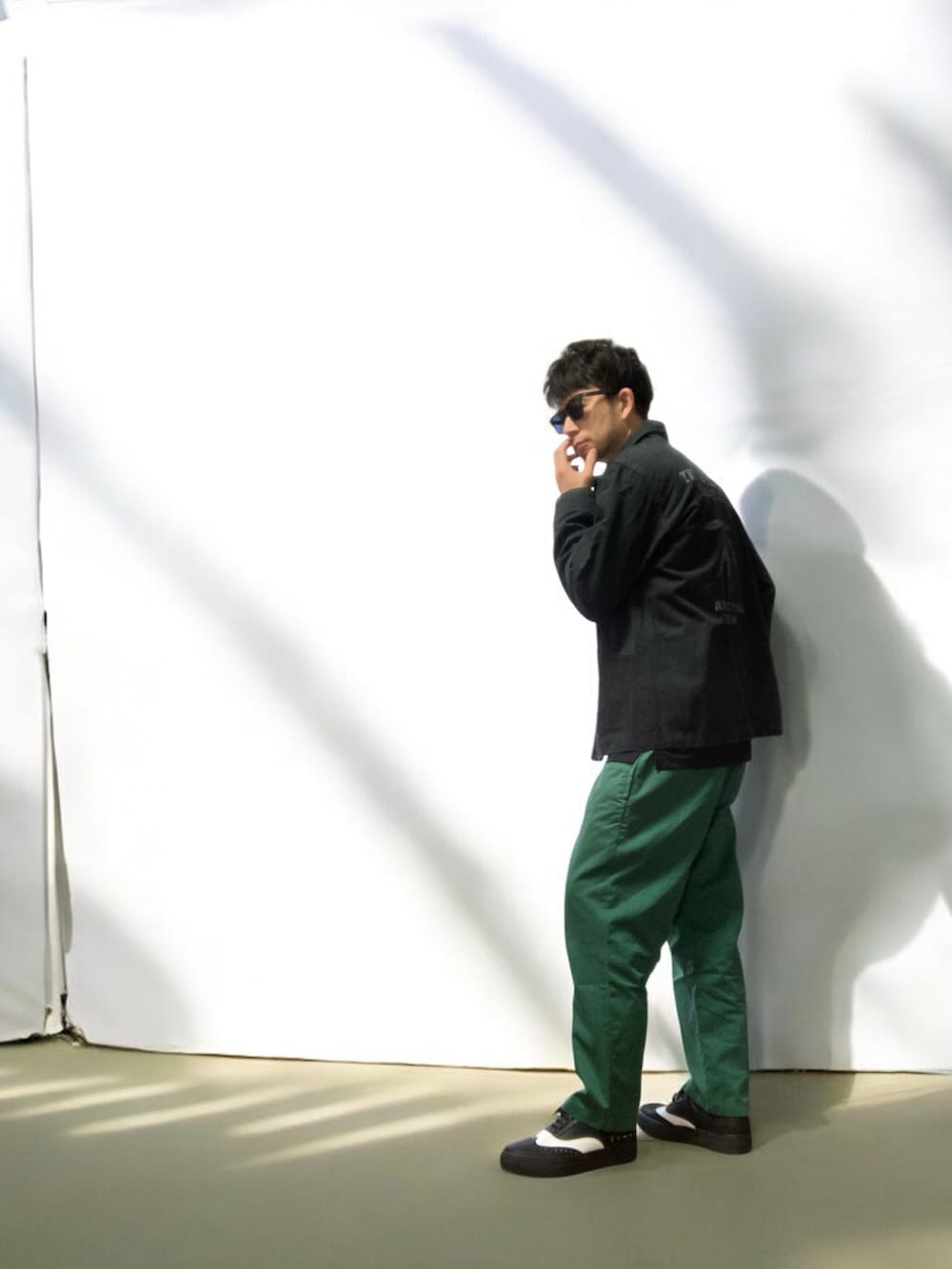 グリーン系のチノパンツ、ブラック系のスニーカー、ブラック系のジャケット/アウターを着用したメンズの春コーディネートの3枚目の写真