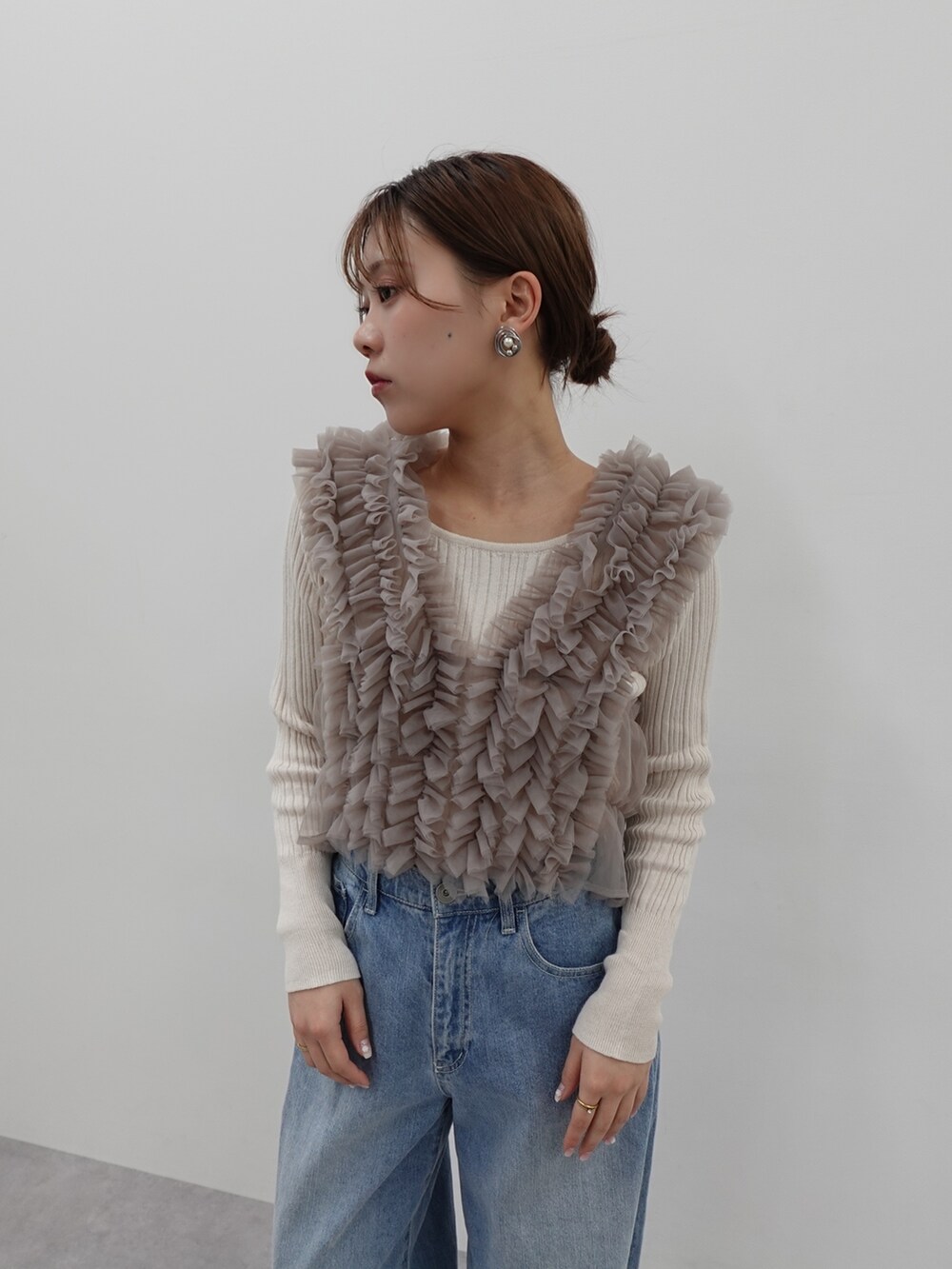ベージュ系のベスト、ブルー系のデニムパンツ、ブルー系のデニムパンツを着用したレディースの冬コーディネートの2枚目の写真