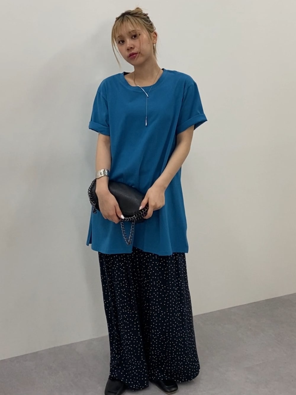 ブルー系のチュニック、ブラック系のその他パンツを着用したレディースの夏コーディネートの2枚目の写真