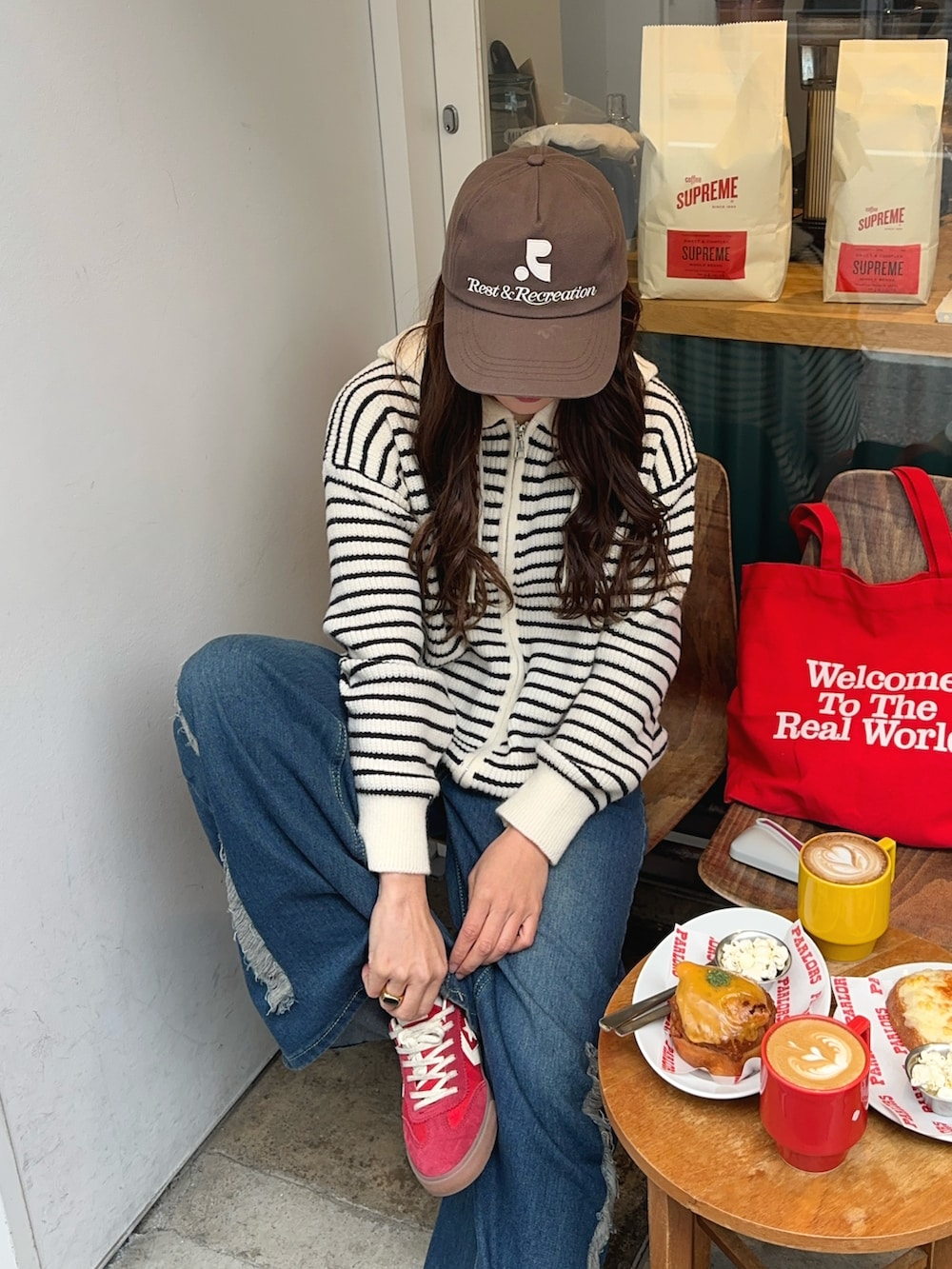 レッド系のスニーカー、ブラウン系のキャップを着用したレディースの冬コーディネートの3枚目の写真