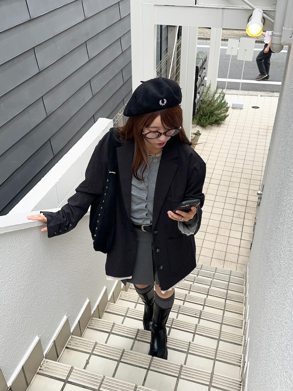 ブラック系のテーラードジャケット、ブラック系のブーツ、グレー系のスカートを着用したレディースの秋コーディネートの3枚目の写真