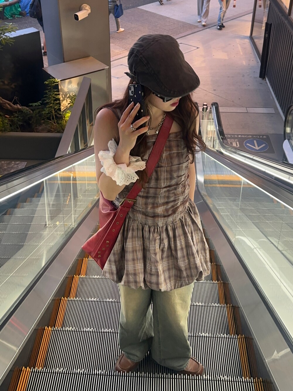 レッド系のショルダーバッグ、ブラウン系のワンピース、ブルー系のデニムパンツを着用したレディースの夏コーディネートの3枚目の写真
