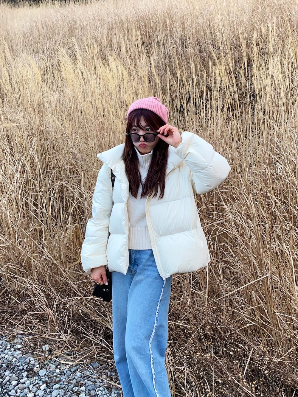 ブラウン系のショルダーバッグ、グレー系のスニーカー、ブルー系のデニムパンツを着用したレディースの冬コーディネートの3枚目の写真