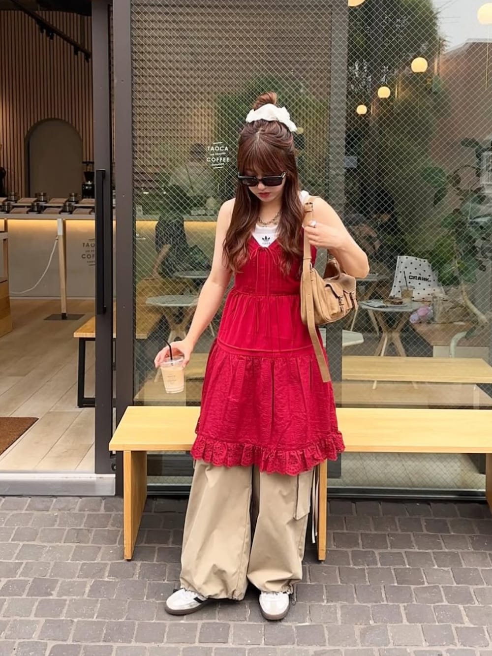 レッド系のワンピース、ベージュ系のカーゴパンツ、ホワイト系のスニーカーを着用したレディースの夏コーディネートの3枚目の写真