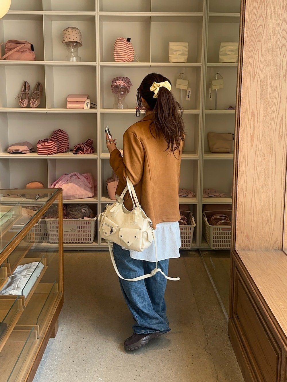 ベージュ系のテーラードジャケット、ブラウン系のローファー、ブルー系のデニムパンツを着用したレディースの春コーディネートの3枚目の写真