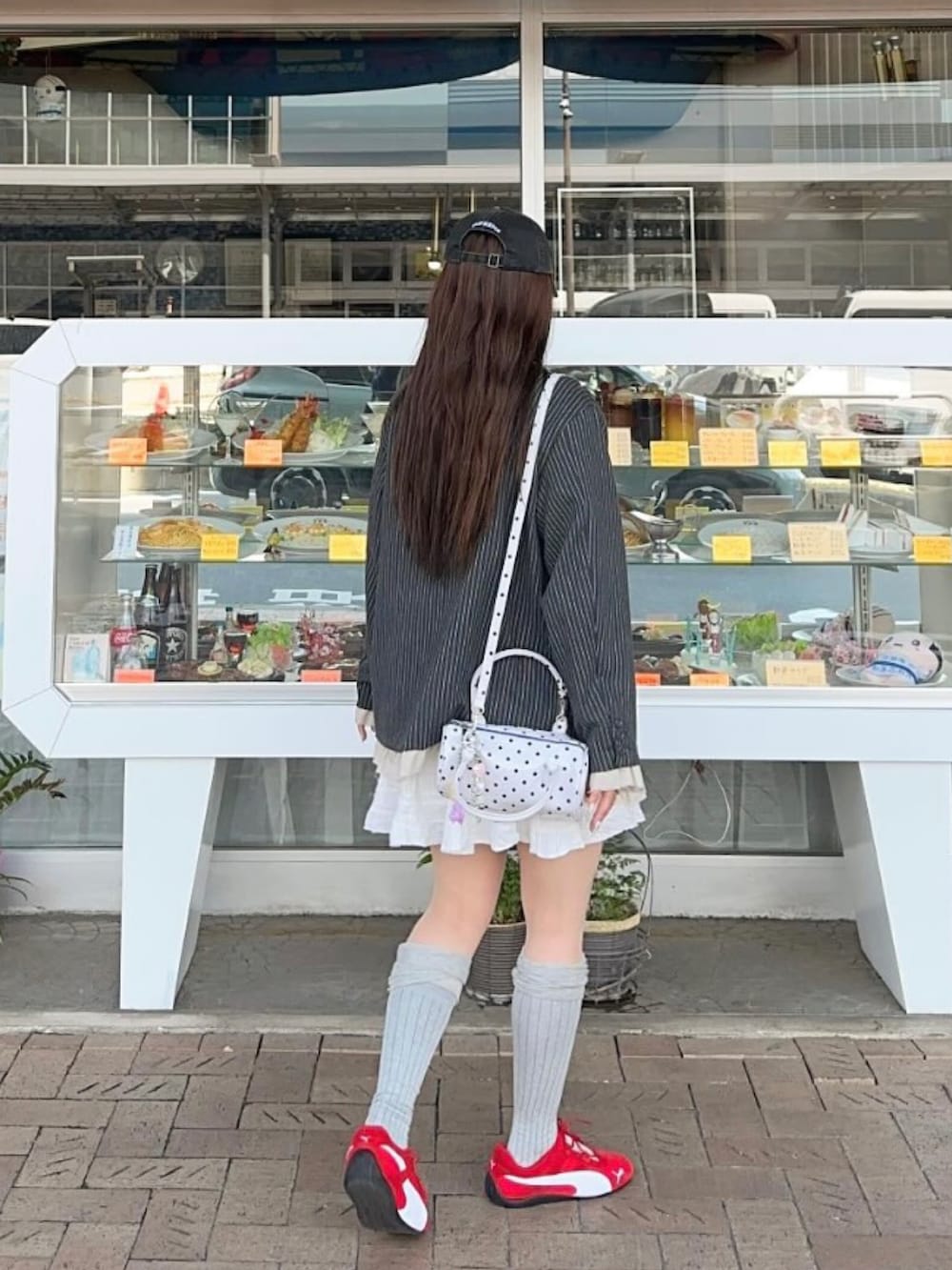 グレー系のテーラードジャケット、ホワイト系のスカート、レッド系のスニーカーを着用したレディースの春コーディネートの2枚目の写真