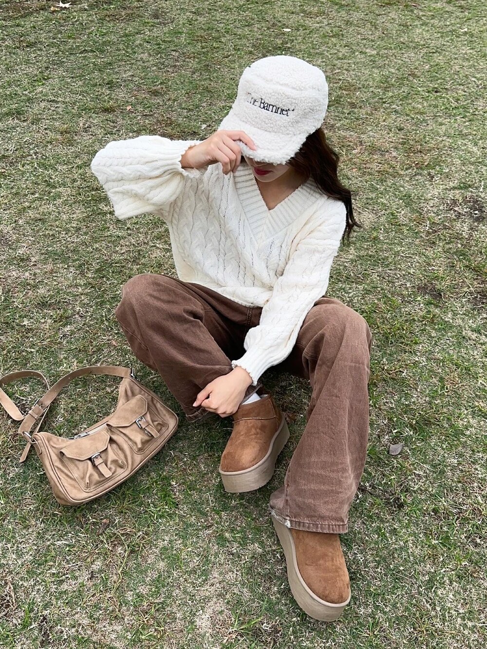 イエロー系のハンドバッグ、ブラウン系のデニムパンツ、ホワイト系のトップスを着用したレディースの秋コーディネートの2枚目の写真