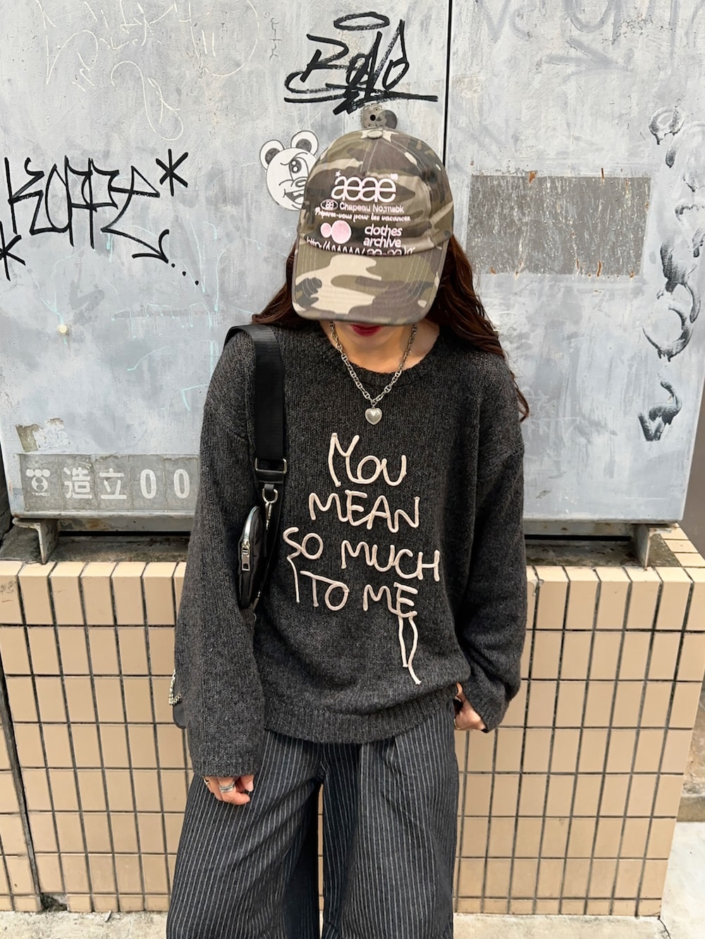 ブラック系のデニムパンツ、ホワイト系のスニーカー、グレー系のニット/セーターを着用したレディースの秋コーディネートの2枚目の写真