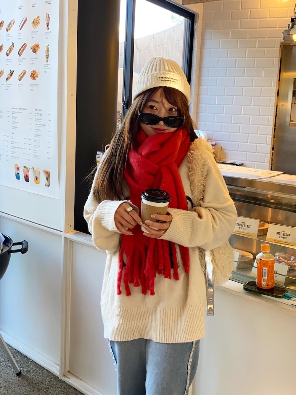 ブルー系のデニムパンツ、ベージュ系のスニーカー、ホワイト系のショルダーバッグを着用したレディースの冬コーディネートの2枚目の写真