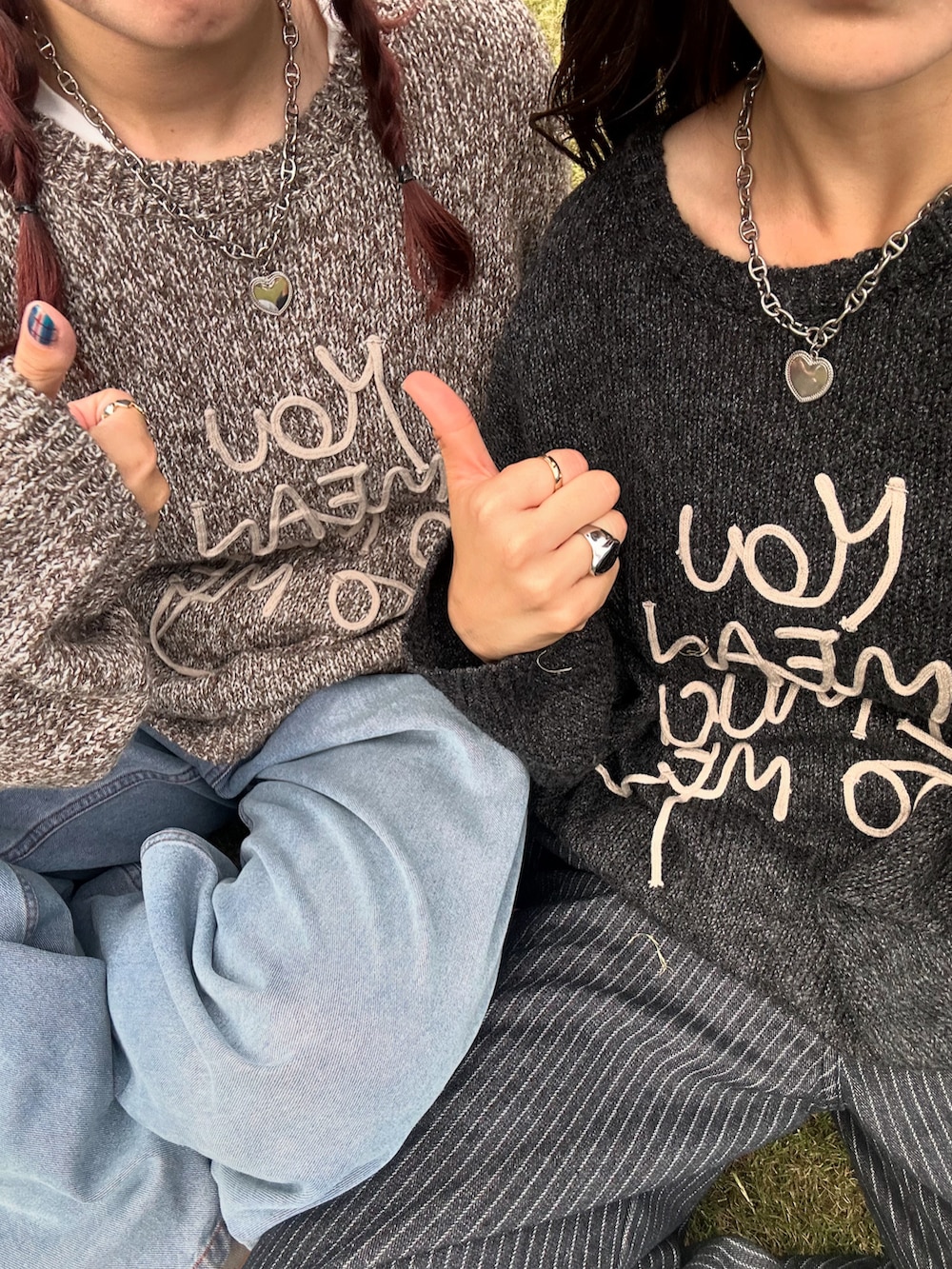 ブラック系のデニムパンツ、ホワイト系のスニーカー、グレー系のニット/セーターを着用したレディースの秋コーディネートの4枚目の写真