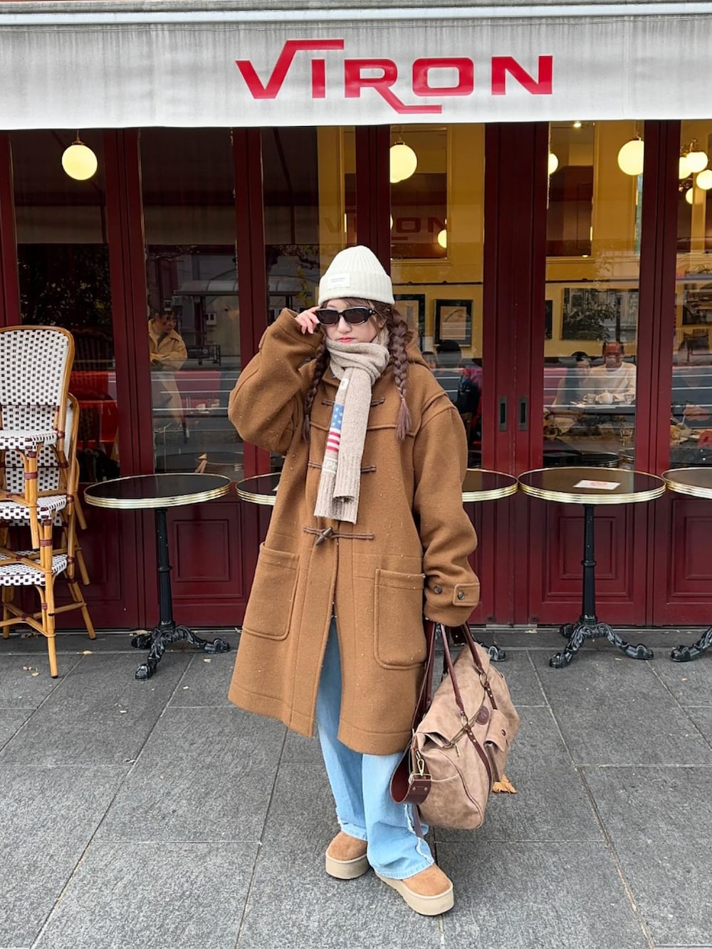 ブラウン系のボストンバッグ、ブルー系のデニムパンツ、ホワイト系のニットキャップ/ビーニーを着用したレディースの冬コーディネートの2枚目の写真