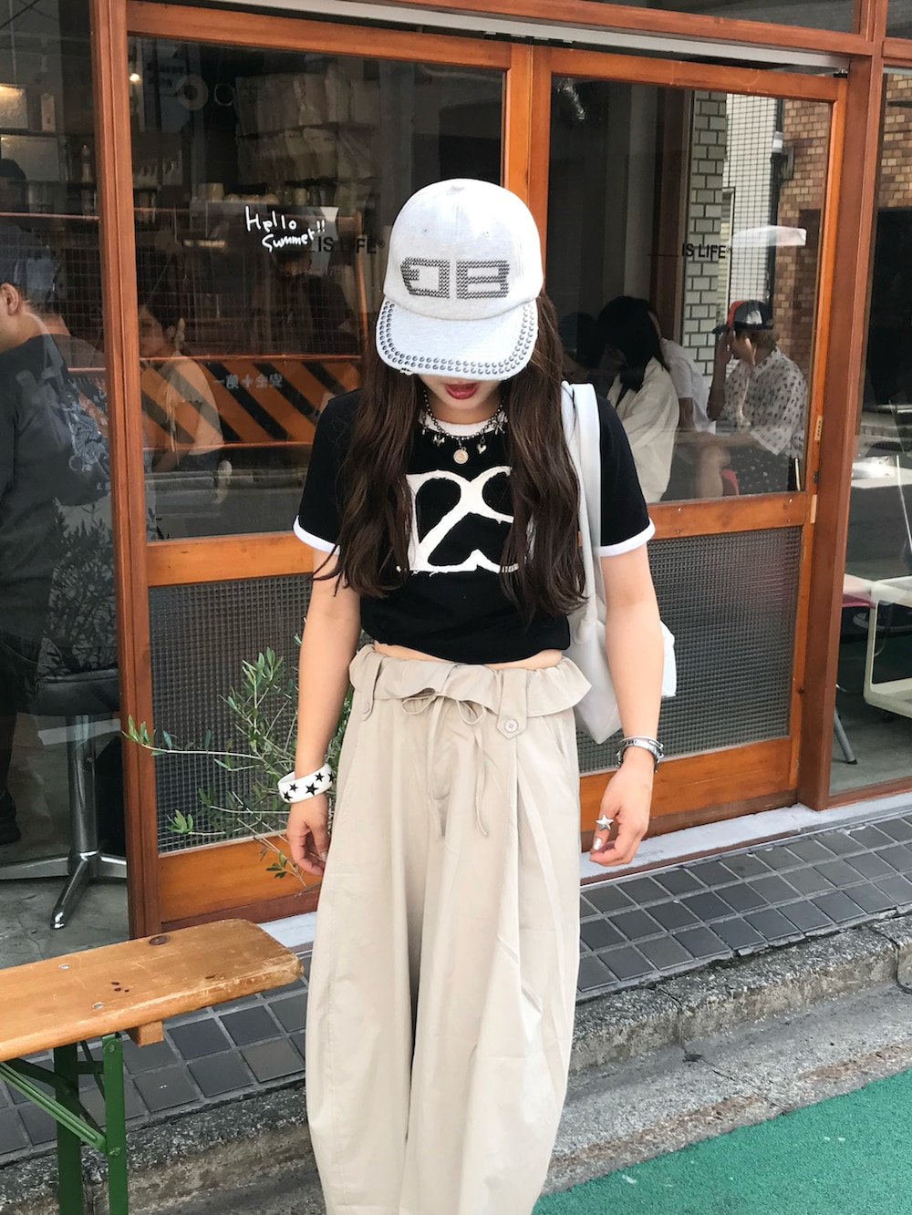 ブラック系のTシャツ/カットソー、ベージュ系のパンツ、ホワイト系のバッグを着用したレディースの夏コーディネートの2枚目の写真