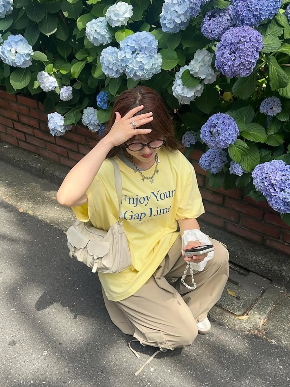 ベージュ系のカーゴパンツ、イエロー系のハンドバッグ、ホワイト系のスニーカーを着用したレディースの夏コーディネートの2枚目の写真