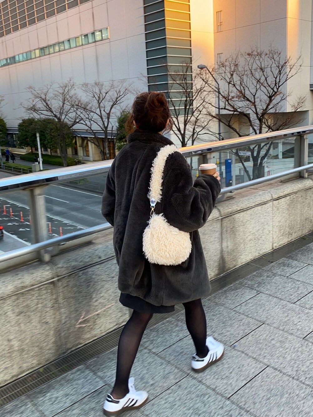 ホワイト系のショルダーバッグ、ホワイト系のスニーカー、ブラック系のスカートを着用したレディースの冬コーディネートの4枚目の写真