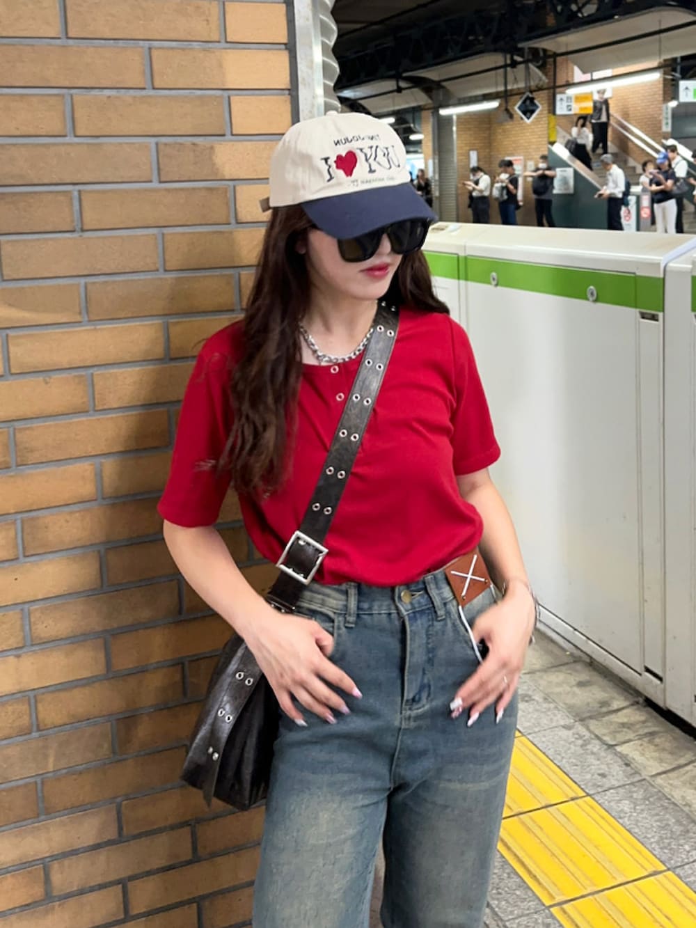 レッド系のTシャツ/カットソー、ブルー系のデニムパンツ、ブラウン系のショルダーバッグを着用したレディースの夏コーディネートの3枚目の写真