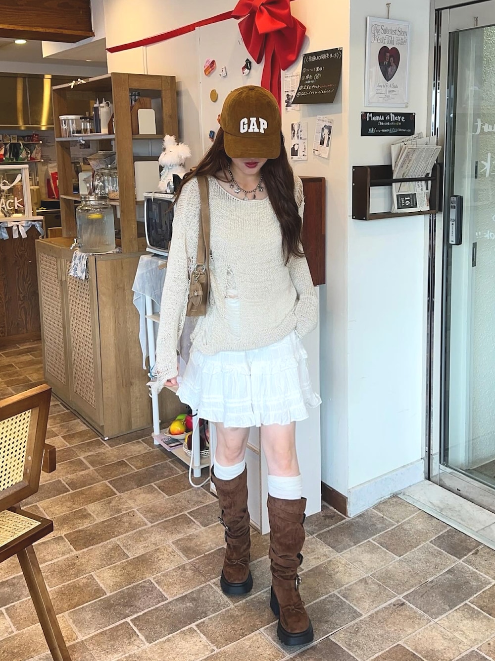 イエロー系のハンドバッグ、ブラウン系のブーツ、ベージュ系のニット/セーターを着用したレディースの秋コーディネートの3枚目の写真