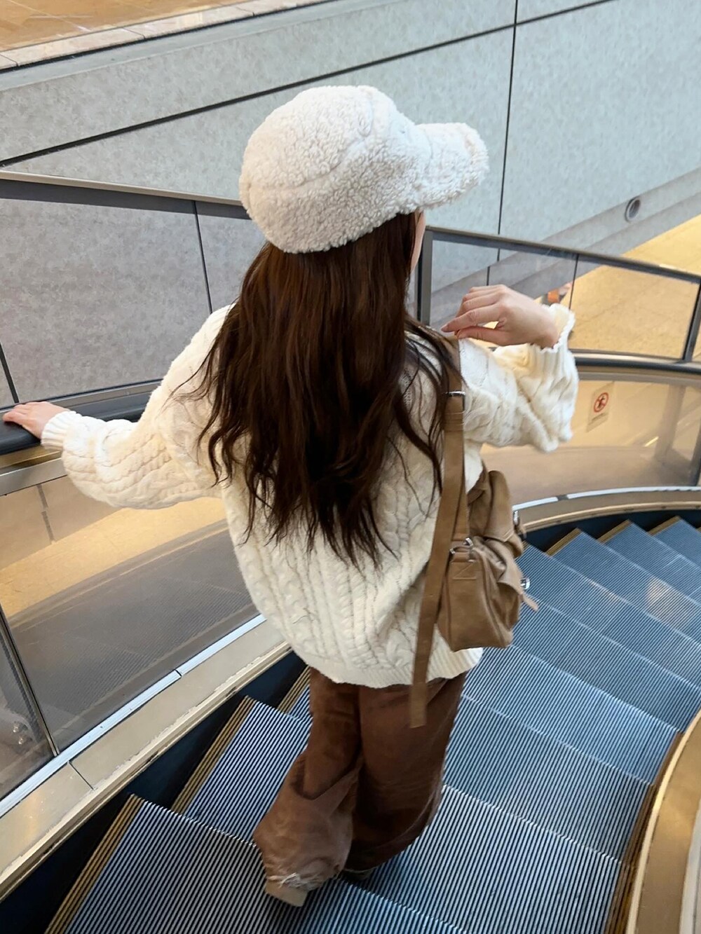 イエロー系のハンドバッグ、ブラウン系のデニムパンツ、ホワイト系のトップスを着用したレディースの秋コーディネートの3枚目の写真