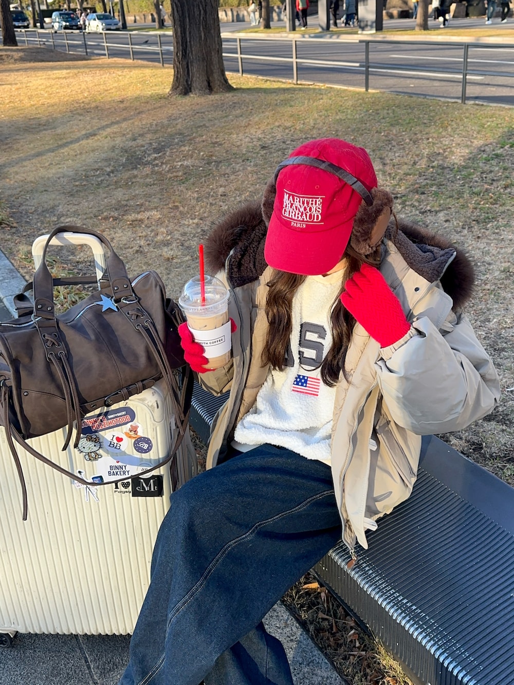 ブルー系のデニムパンツ、レッド系のスニーカー、レッド系のキャップを着用したレディースの冬コーディネートの3枚目の写真